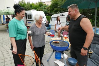 Urlaub vor der Haustür: Warum der Innenhof des Zschopauer Seniorenzentrums für zwei Tage zum Campingplatz wurde - Die 80-jährige Gisela Eisenbach, die mit Sandra Luge auch Federball spielte, freut sich über etwas Stärkung von Grillmeister Falko Oertel.