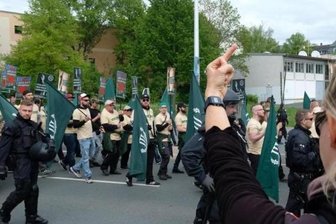 Versammlungsbehörde kann rechtsextremen Aufmarsch in Plauen nicht verlegen - Teilnehmer eines rechten Aufmarsches der Partei "Der dritte Weg" sind zu sehen. Eine Demonstrantin protestiert.