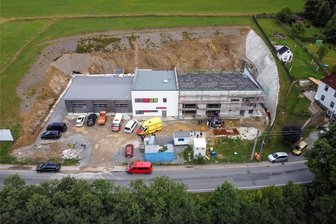 Verspätet und teurer als geplant: Rohbau von Rettungswache im Erzgebirge steht - Der Gebäudekomplex aus Feuerwehrgerätehaus (links) und rohbaufertiger Rettungswache in Steinbach. Rechts neben der Wache ist der Hang zu sehen, der aufwendig gesichert werden musste. Die Böschung auf der anderen Seite und hinter den Gebäuden sorgte ebenfalls für einigen Mehraufwand.