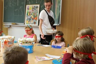 Viel Spaß bei Blindtest mit Früchten - Der Freiwilligendienstleistende Antony Peger verteilt an Kinder der Grundschule in Langenberg bei einem Projekt Früchte. Mit verbundenen Augen sollen diese gekostet und so erkannt werden.