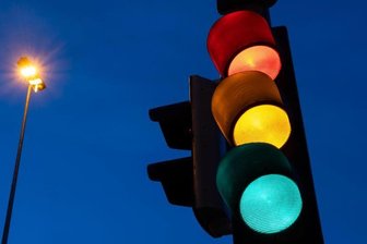            Eine Ampel zeigt am frühen Morgen die Farben rot, gelb und grün.