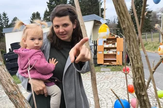 Vierfach-Mama kehrt ins Vogtland zurück: Mit dieser Idee sorgt sie jetzt in Plauen für Gesprächsstoff - Maria Lässig und das jüngste ihrer vier Kinder freuen sich in Jößnitz auf Ostern - im Hintergrund ist der Verkaufsschrank zu sehen.