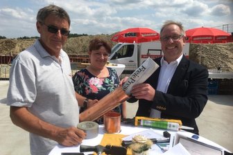 Vogtland: Metzgerei Dölz legt Grundstein für Bistro und Hofladen - Ein Zeugnis für die Nachwelt: Polier Frank Brenner (links) sowie Mandy und Heiko Dölz haben bei der Grundsteinlegung eine aktuelle Ausgabe der "Freien Presse" in die Kartusche gesteckt. Eine Kopie des Meisterbriefs, ein abgearbeitetes Fleischermesser und ein Säckchen Kleingeld fanden dort ebenfalls ihren Platz.