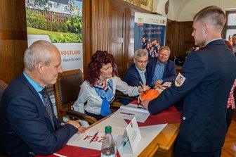 Vogtland und Westerzgebirge kooperieren bei Ausbildung des Feuerwehr-Nachwuchses - Treuens Bürgermeisterin Andrea Jedzig (parteilos) unterschreibt symbolisch auf dem Helm von Jugendfeuerwehrwart Erik Jedzig. Hintergrund ist eine Kooperation bei der Ausbildung von Feuerwehr-Nachwuchs.