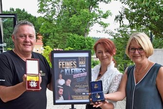 Vogtlandhalle Greiz präsentiert neues Veranstaltungsformat - Charly Breitzmann (links, mit einem Schwedischen Schwerterorden) und Christine Colditz (rechts, mit einem mit Brillanten und einem Rubin besetztes Faberge-Amulett) bieten in Greiz drei Tage lang Show, Schätzen, Handeln und Spaß rund um das Thema Antiquitäten. Die Leiterin des Veranstaltungshauses, Ann-Katrin Gabel, hat die Verbindung geknüpft.