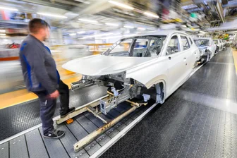 Vom Elektroauto zurück zum Verbrenner: VW-Werker aus Zwickau sollen jetzt in Wolfsburg mit anpacken - Ein Mitarbeiter steht im VW-Stammwerk in Wolfsburg vor der Karosserie eines Tayron.