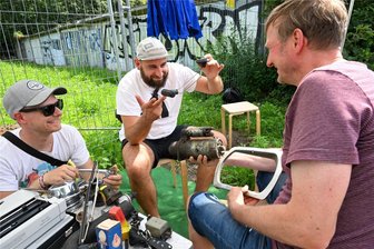Von Anlasser bis Zündkerze: Darüber freut sich ein Künstler in Chemnitz - Jakob Heinzmann vom Kulturhauptstadt-Team, Künstler Martin Maleschka und Uwe Fretsch (von links). Uwe Fretsch gab Autoteile aus der Garage seines Vaters für das Kunstprojekt ab, darunter den Anlasser eines Wartburgs (Mitte).