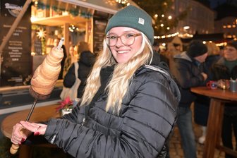 Von exotischer Neuheit bis zur süßen Versuchung: Was Weihnachtsmärkte im Erzgebirge kulinarisch zu bieten haben - Florin Marie Müller vom Team des Baumstriezel-Standes auf dem Schneeberger Weihnachtsmarkt präsentiert die süße Leckerei.