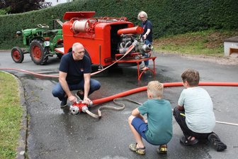 Von Holland in Zwickaus kleinsten Ortsteil: Familie hat sich super eingelebt - Die stellvertretende Jugendwartin Daniela und ihr Mann Bob van den Dobbelsteen erklären zwei Jugendlichen die Funktionsweise einer Tragkraftspritze.