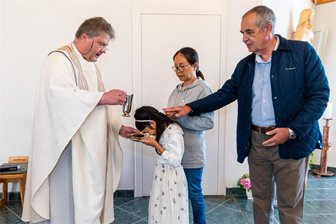 Von Vietnam ins Erzgebirge: Nach Einschulung geht Anh Thu den nächsten Schritt - Pfarrer Andreas Eckert tauft Anh Thu im Beisein von Oma Thi Ai Phi Le und Opa Wilhelm Schlax in der katholischen Kirche in Olbernhau.