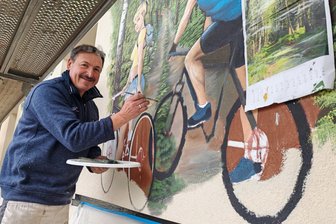 Vor Jahren geschlossene Pension im Erzgebirge kehrt als Hotel zurück - Die Radler benötigen noch einige Pinselstriche. Andreas Schott bei der Arbeit am Wandbild des neuen Hotels.