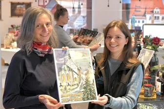 Vorfreude: Diese Adventskalender sind „echt Freiberg“ - Ingunn Abraham (l.) zeigt Jasmin Faust von der Touristinformation am Schlossplatz in Freiberg den Silberstadt Freiberg Schoko-Adventskalender 2023, den sie gestaltet hat.