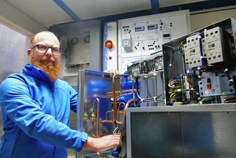 Wärmepumpen: Firma Rochhausen in Scharfenstein macht Lehrlinge fit - Vor einem Lehrmodell an der Wand nimmt Geschäftsführer Tobias Rochhausen eine echte Wärmepumpe unter die Lupe. 