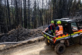 Waldbrand in tschechischem Grenzgebiet unter Kontrolle - Feuerwehrleute fahren mit einem geländegängigen Einsatzfahrzeug auf einem Waldweg.