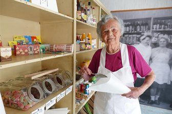 Waldkirchener DDR-Konsum wird fürs Heimatfest wieder geöffnet - So wie in den 1970er-Jahren - der frühere Alltag ist auf einem großen Wandbild im Hintergrund dargestellt - steht Magdalena Ulm wieder im früheren Lebensmittelladen an der Dorfstraße.
