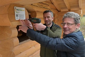 Wander-Schutzhütten im Erzgebirge zieren jetzt Gütesiegel für einheimisches Holz - Clemens Weiser vom Forstbezirk (li.) und Philipp Strohmeier von „Holz von hier“ bringen das Gütesiegel an.
