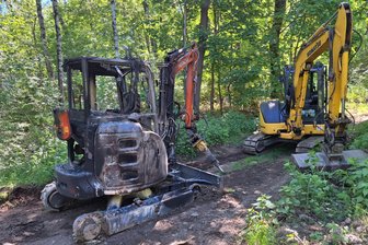 Wanderer findet abgebrannten Bagger in Chemnitzer Wald - Der abgebrannte Bagger wurde von einem anderen Bagger aus dem Wald gezogen.