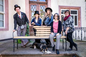 Wandergesellen verabschieden sich mit raffiniertem Geschenk von Schloss Wolkenburg - Die Wandergesellen Vitus, Meta und Charlotte übergeben als Gastgeschenk eine Bank an Museumsleiterin Barbara Wiegand-Stempel und Wolkenburgs Ortsvorsteherin Annett Groh (von links)