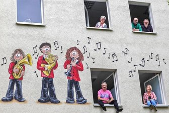 Wandgemälde Bernsdorf: Ein ganzes Orchester ist leichter gemalt als eine halbe Note - Frech und bunt statt trist und grau: Bürgermeisterin Roswitha Müller, Orchesterchef Andreas Günther, Vorstandsmitglied Sven Hoffmann (oben von links), Künstler Jens „Tasso“ Müller und Gestalterin Juliane Burgstaller freuen sich über die neue Fassadengestaltung an der Kultur- und Sporthalle.