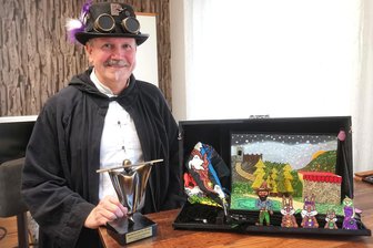 Warum der Chef-Magier von Zwickau am liebsten für Kinder zaubert - Lutz Fischer zu Hause in Zwickau-Weißenborn mit seinem Preis. Auf sein altes Zauberbuch ist er besonders stolz. Das lässt sich aufklappen wie kleine Bühnenbilder mit Figuren. Dazu erzählt er Märchen, geeignet für Kindergartenkinder. „Das kommt sehr gut an“, sagt der Magier.