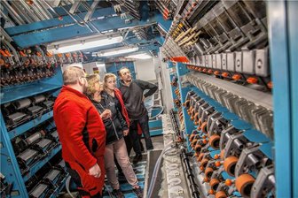 Warum die Firma Otex in Flöha eine Texturiermaschine und eine Tischtennisplatte in Betrieb nimmt - Robert Wobst (vorn), Teamleiter Mechanik und Instandhaltung, erläutert den Kolleginnen und Kollegen die neue Texturiermaschine, die zurzeit noch im Probebetrieb läuft. 