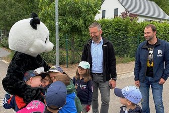 Warum ein Panda durch Böhrigen stapft - Heißgeliebter Panda: Kinder aus der Kita Böhrigen bestürmen das WWF-Wappentier. Edeka-Betriebsleiter Stephan Kleyer (M.) und Ortsvorsteher Philipp Resch freuen sich über die gelungene Aktion.