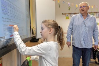Warum in Thum jetzt sogar Lehrer zum Lernen an die Tafel kommen - Finger statt Kreide: Kim Hunger aus der Klasse 3b im Mathe-Unterricht mit Schulleiter Michael Preißler an einer der nagelneuen digitalen Tafeln in der Grundschule in Thum.