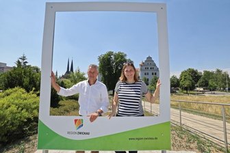 Warum jetzt im Muldeparadies ein riesiger Bilderrahmen steht - Die Zwickauer OB Constance Arndt und der Beigeordnete des Landkreises Carsten Michaelis zeigten schon einmal, mit welcher Kulisse im Hintergrund man sich hier fotografieren lassen kann. 