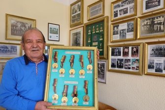 Warum Kunstradsportler getrennte Wege gehen - Joachim Schnabel im Vereinszimmer der alten Oberschindmaaser Schule vor historischen Kunstradsport-Fotos - und mit DDR-Meister-Medaillen, die sein Sohns Jens Schnabel gewonnen hat.