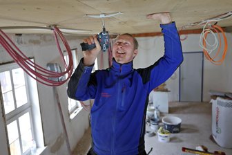Warum wird schon wieder im Stadthaus Hohenstein-Ernstthal gebaut? - Karsten Meyer von Bergmann Elektrotechnik Hermsdorf fixiert Kabel neu an der Decke.