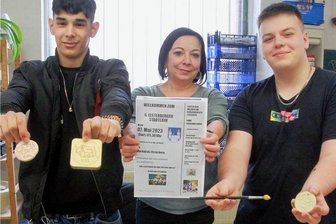 Was das Elsterberger Brunnenfest am Wochenende zu bieten hat - In der Plauener Fördergesellschaft für berufliche Bildung wurden die Medaillen für den 6. Stadtlauf in Elsterberg angefertigt. Im Bild zeigen Werkstatt-Pädagogin Kathrin Petermann, Antonio Ramon Rodriguez Mayan (links) und Tyler Langheinrich die Medaillen.