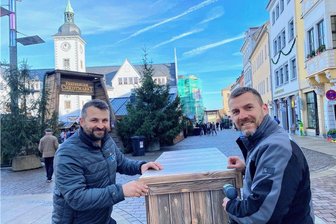 Was es mit den dekorativen Holzkisten vor dem Christmarkt in Freiberg auf sich hat - Robert (r.) und Sebastian Liebscher von der Firma "Druckgemacht" in Freiberg verhüllten die Betonklötze an den Eingängen des Christmarktes, hier an der Peterstraße.