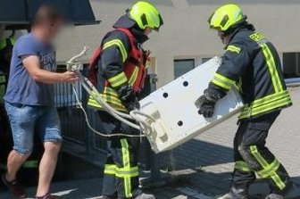 Waschmaschine gerät in Brand - Feuerwehrleute trugen die Waschmaschine aus dem Ärztehaus Heide ins Freie.
