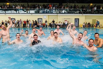 Wasserball-Bundesliga: SVV Plauen feiert mit Sieg gegen München den Klassenerhalt - Die Siegesfeier nach dem Klassenerhalt. Trainer Maik Bielefeld (vorn Zweiter von links) musste mit Klamotten ins Becken.