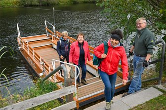 Wasserschänke im Zschopautal: Fährfest zum Saisonende, 0-Euro-Schein und Schließzeit - Eine dreiköpfige Wandergruppe ist mit der Fähre „Anna“ in Krumbach angekommen. Fährmann Ronald Hornauer begrüßt die Frauen. Erstmals wird zu Saisonende ein Fährfest gefeiert. Und es gibt weitere Neuigkeiten aus der Wasserschänke.