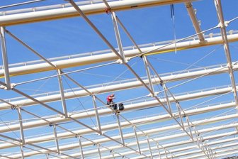 Webalu-Eröffnung in Werdau verschiebt sich auf unbestimmte Zeit - Einsam und verlassen sitzt ein Bauarbeiter auf der neuen Dachkonstruktion im Webalu. Er genießt dort weder die Aussicht noch die Mittagssonne, sondern zieht Schrauben fest.