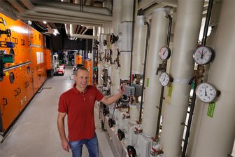 Wegen Sanierung: HOT-Badeland bleibt 2024 ein halbes Jahr zu - Badbetreiber Thomas Sprunk in den Technikräumen des HOT-Badelandes. Die Heizungsregister (rechts) müssen ebenso erneuert werden wie viele Teile der Lüftung, welche sich hinter den orangefarbenen Verkleidungen verbirgt.