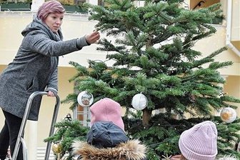 Weihnachtsmarkt in Markneukirchemn zieht um: Museumshof statt Innenstadt - Alles ist vorbereitet: Am Mittwochnachmittag schmückten Kinder aus der Kita Abenteuerland - sie durften nur von hinten fotografiert werden - mit Josefine Grumbach von der Stadtverwaltung den Baum im Hof des Musikinstrumenten-Museums. Am Samstag ist Museumsweihnacht.