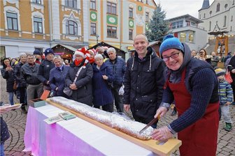 Weihnachtsmarkt in Meerane eröffnet: Alle Tipps für Besucher - Der XXL-Stollen gehört zum Weihnachtsmarkt in Meerane: Bäckermeister Michael Dicke und Bürgermeister Jörg Schmeißer (von rechts) beim Anschnitt am Freitagnachmittag.