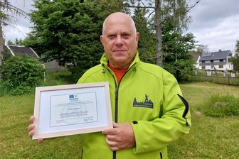 Weltkulturerbe Flößerei: Ein Vogtländer mischt international mit - Bernd Kramer, Vorsitzender des Flößervereins Muldenberg, wurde für weitere drei Jahre als 2. Vizepräsident der Floaters and Raftmen International Association gewählt. Er hat großen Anteil daran, dass die Unesco 2022 das Flößen zum Immateriellen Kulturerbe erhoben hat. Die Urkunde in seinen Händen bestätigt dies.