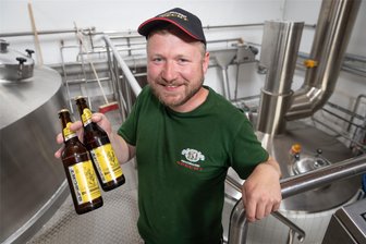 Weniger Umsatz im Sommer: Mit diesen Biersorten wollen Brauereien im Erzgebirge punkten - Nick Morgenstern, Geschäftsführer der Ehrenfriedersdorfer Specht-Brauerei, zeigt zwei Flaschen Bergmannsbier. Diese Sorte ist im Werksverkauf aktuell sehr gefragt.