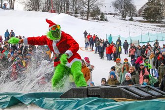 Wenn der Grinch übers Wasser gleitet: Action-Event im Erzgebirge lockt hunderte Besucher an - Der Grinch alias David Troll auf dem Snowboard: Er belegte beim Water-Slide-Contest in Johanngeorgenstadt einen der vorderen Ränge. Vor allem bei den zahlreichen Kindern vor Ort, war sein Kostüm sehr beliebt.