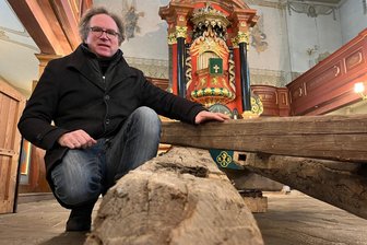 Wer will diese alten Balken haben? Kirchgemeinde im Erzgebirge versteigert Turmholz und Nägel - Der Zöblitzer Pfarrer Wolfram Rohloff neben den Balken im Kirchenschiff.