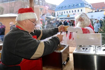 Wie die Suppenküche auf der Zwickauer Schlossweihnacht die Herzen erwärmt - Da greift sogar der Weihnachtsmann gern zu. Rainer Kaubisch reicht ihm die Suppe (Einheitspreis: 5 Euro) über die Theke. Der Stand befindet sich zentral im Burggraben hinterm Schloss Osterstein.