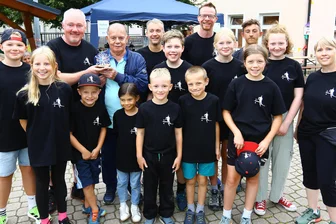 Wie ein Radsportler vor 50 Jahren den Biathlonsport in einem Dorf im Erzgebirge ins Rollen brachte - Der Biathlon-Abteilungsleiter der TSG Sehma, Ronny Orgis, übergab im Rahmen des Vereinsfestes zusammen mit den Nachwuchssportlern einen Pokal an Gründungsmitglied Günter Süß.