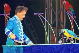 Wie einem Zirkus in Plauen ein Show-Programm ohne große Wildtiere gelingt - Ein bunter Farbtupfer der Show: Ivan Medini lässt einen seiner Papageien mit dem Drahtesel fahren. 