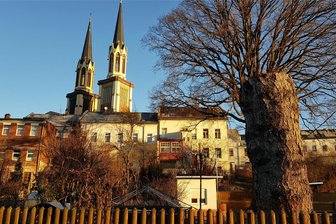 Wie Oelsnitzer den Nordturm der Jakobikirche retten wollen - Die 73,5 Meter hohen Doppeltürme der Oelsnitzer Jakobikirche - das Foto entstand am Montagmorgen vom Jahnteich aus - sind die höchsten Kirchtürme im Vogtland. Der Nordturm (links im Bild) ist in schlechtem Zustand. Neben einer Sanierung wurde auch ein Rückbau bis auf den Umgang erwogen.