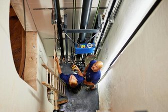 Wie sich der Reichenbacher Aufzugsbauer Orba-Lift verjüngt und wächst - Franz Kapke (Mechatroniker im 4. Lehrjahr/links) und Chris Wolf von Orba-Lift beim Bau des verglasten hydraulischen Personenaufzuges im Smart Rail Connectivity Campus, der gerade im Unteren Bahnhof in Annaberg-Buchholz entsteht.