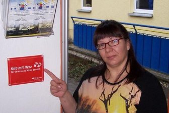 Wie sich in Oederan ein Berufswunsch erfüllte - Hier geht ein Berufswunsch in Erfüllung: Christina Müller an der Plakette "Kita mit Herz" im Oederaner "Sonnenland". 