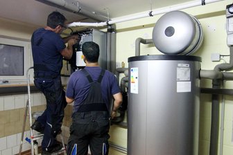 Wie weiter mit dem Heizungsgesetz? - Handwerker schließen im Keller eines Wohnhauses eine Wärmepumpe an. Die Heizungsbranche braucht Planungssicherheit.